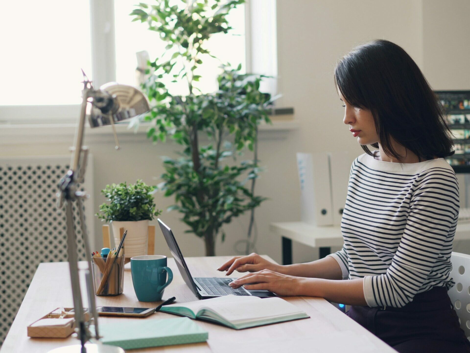 une femme assise à un bureau tape sur le clavier d’un ordinateur portable