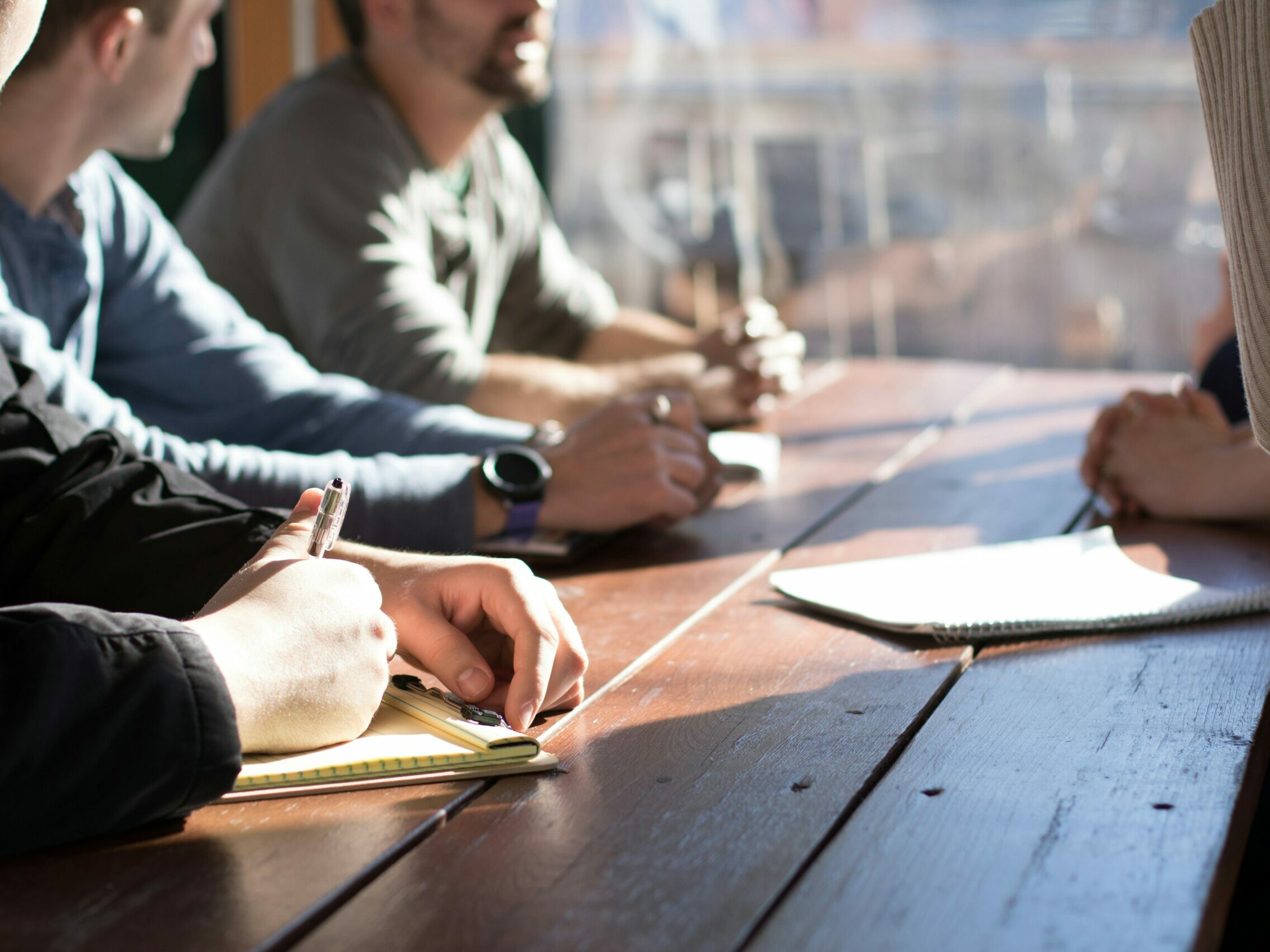 personnes assises sur une chaise devant une table tout en tenant des stylos